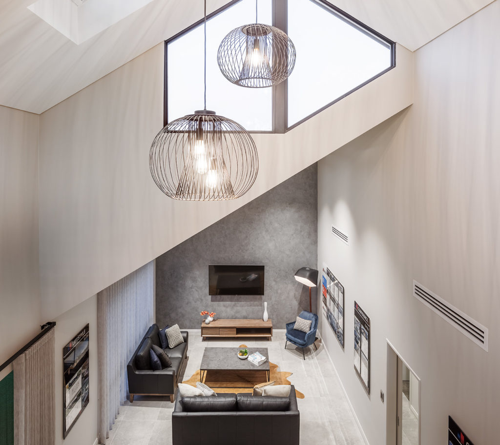 Large pendant lights hanging from high sloped ceiling with skylight