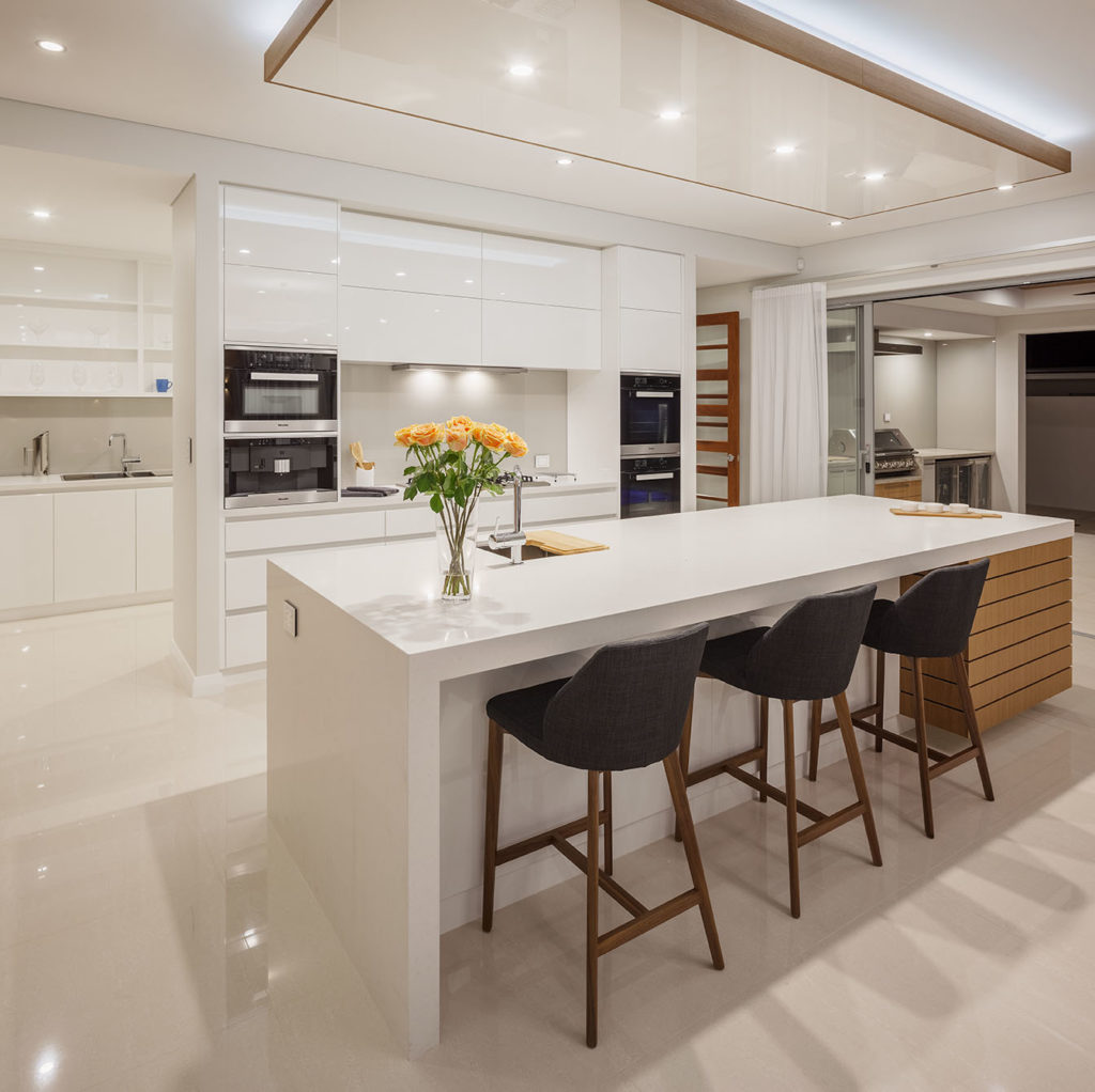 Modern white Kitchen with chairs alongside island bench